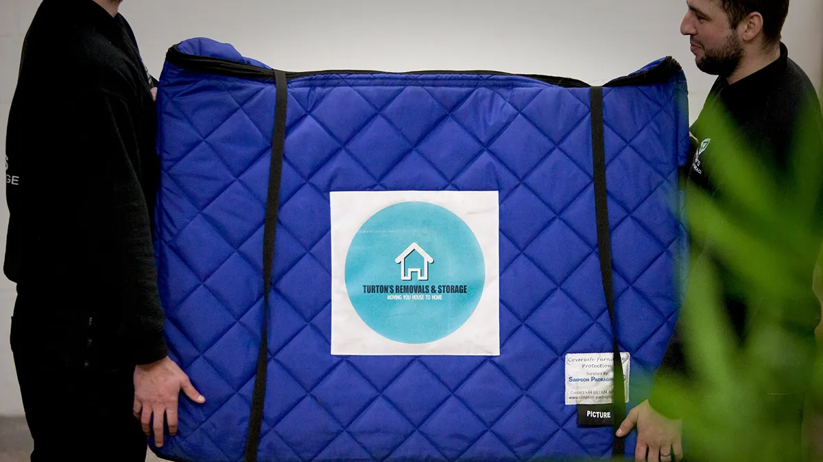 Turton's movers carry removal boxes wrapped in protective covers for a household move